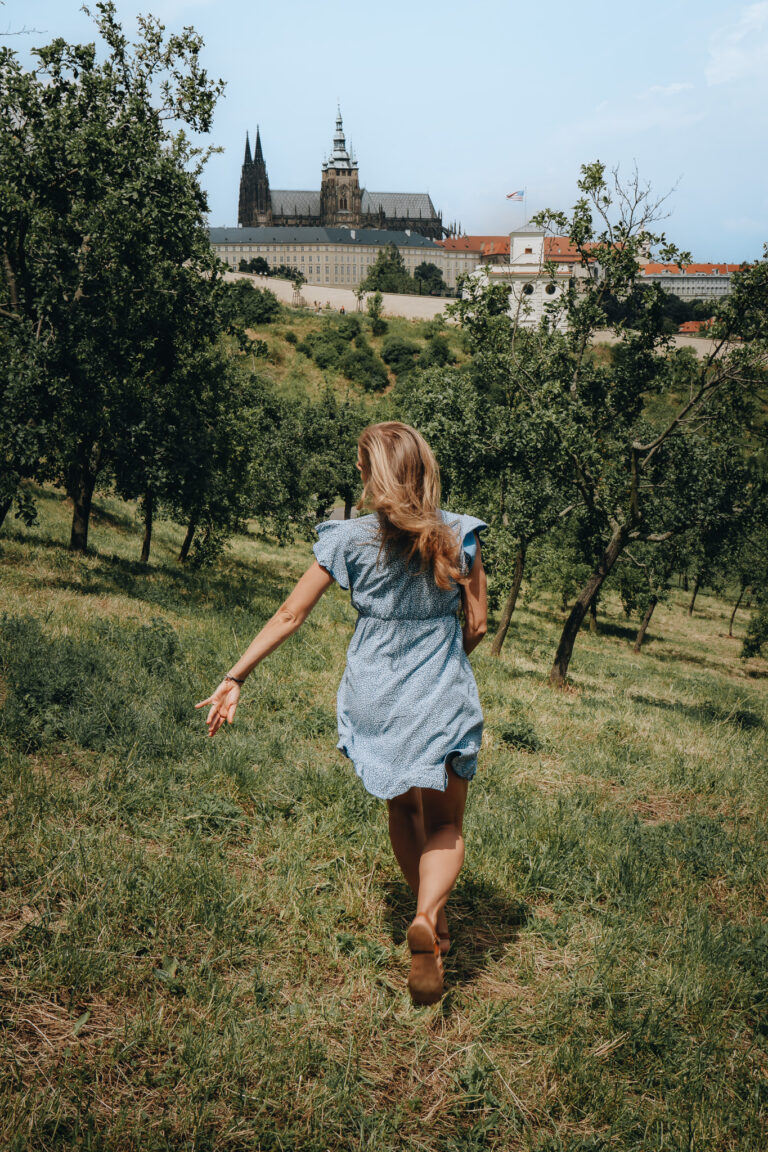 Lifestyle portrét - žena v modrých šatech běžící přes Petřín